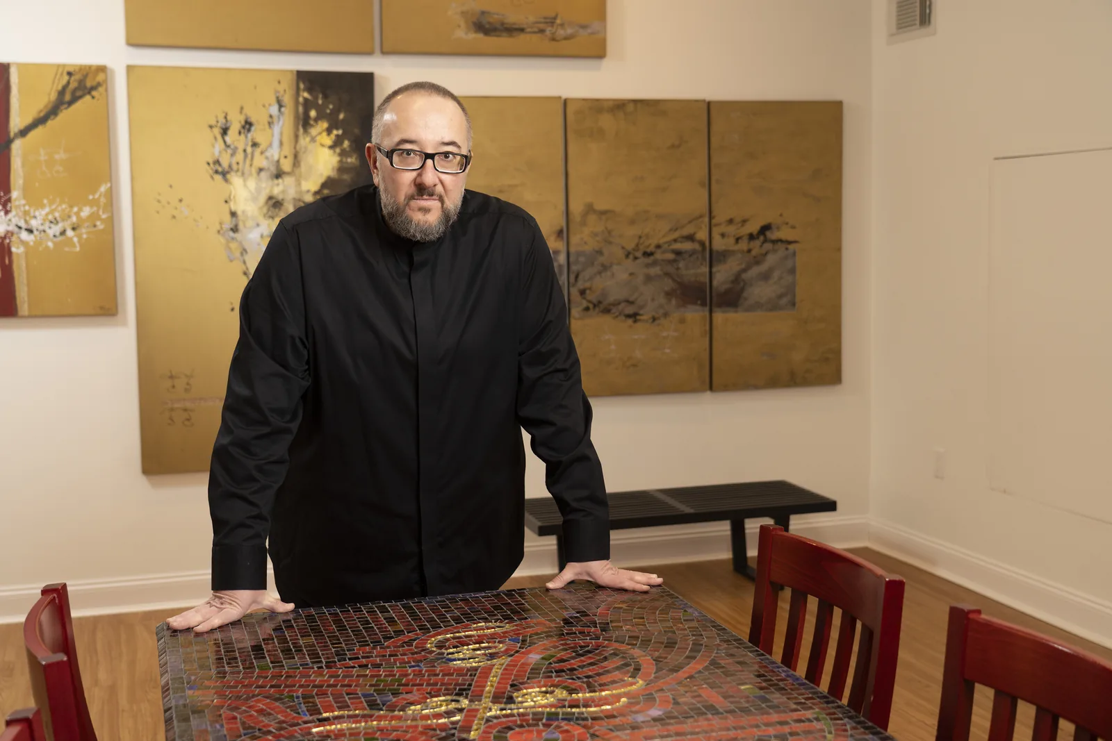 An artist standing among original works prepared for reproduction photography